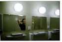 Sängerin Rosa Anschütz in öffentlicher Toilette schaut in den Spiegel