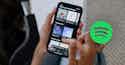 Spotifys Bundling Practices Implications for Songwriters and Publishers meta Hand holding smartphone displaying Spotify music app interface with album covers and playlists. Green Spotify logo visible in corner.