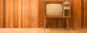 old TV set in front of a wooden paneled wall