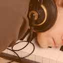Joven con auriculares durmiendo sobre un teclado